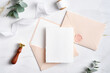 Feminine wedding invitation. Blank paper card mockup, pink envelopes, silk ribbon, eucalyptus, wax seal stamp on marble table. Wedding stationery template.