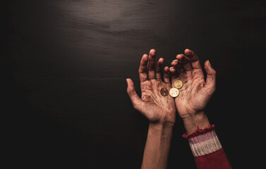 Poverty - kid begging for money. Dirty skinny beggar child’s hands with coins on black.