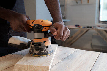 Wall Mural - Close up of black carpenter sanding wood using electric tool in workshop, copy space