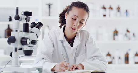 Wall Mural - dedicated to science. 4k video footage of a young scientist using a microscope and writing down note