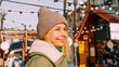 © brillianata - Young blonde at the European street food fair. She is happy and smiling on a sunny winter day. Blurred background of various street food sales points