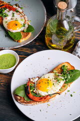 Wall Mural - delicious and appetizing bruschetta with fried eggs and herbs for breakfast