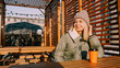 © brillianata - Happy woman on a winter sunny day at a street food fair in space for relaxing and meeting friends. She drinks coffee or mulled wine from an orange cup