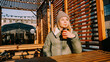 © brillianata - Happy woman on a winter sunny day at a street food fair in space for relaxing and meeting friends. She drinks coffee or mulled wine from an orange cup