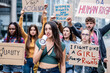 Young woman with megaphone leading a multiracial group of people in a stike for equality and women rights, activits in protest in the city