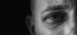 © Ralf Geithe - Dunkle Aufnahme eines traurigen Mannes mit einem weinenden Auge im Detail