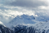 Fototapeta Góry - Snow covered Alps peak with cloudy sky background during winter day.