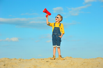 Little boy with a megaphone against the blue sky.