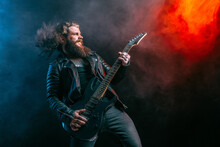 Expressive Man Rock Guitar Player With Long Hair And Beard Plays On The Smoke Background. Studio Shot