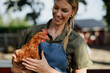© Halfpoint - Cheerful farmer woman holding hen outdoors at farm.