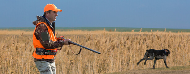 Wall Mural - Hunter man in camouflage with a gun during the hunt in search of wild birds or game. Autumn hunting season.