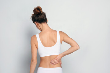 Wall Mural - Woman suffering from pain in back on light grey background