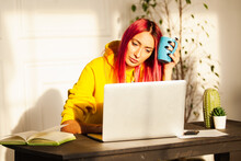 An Adult Girl With Pink Hair At A Laptop