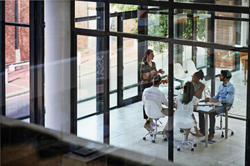 leading her team through the meeting. shot of a group of businesspeople having a meeting in a boardr