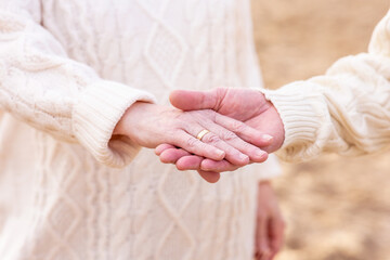 Canvas Print - A closeup of the elderly couple. The man holding the woman's hand with a golden ring.