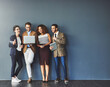 © Delmaine Donson/peopleimages.com - The connected team is an efficient team. Studio shot of a group of businesspeople using wireless technology together while standing in line against a gray background.