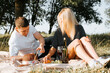 © Sergio - Romantic picnic, date outdoors, valentine's day concept. Young handsome caucasian heterosexual couple eating fruits resting on blanket outdoors on sunny day