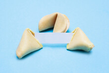 Broken Fortune Cookies On A Blue Background And Place For Text. Mockup. Blank Paper For Writing A Fortune.