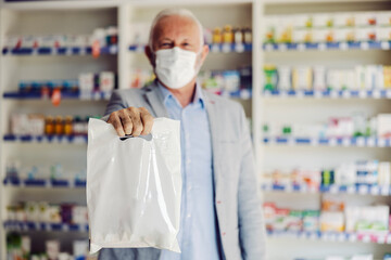 Wall Mural - A senior man holding bag with drugs, medicines and vitamins he purchased at pharmacy.