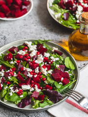 Wall Mural - Arugula, Beet and cheese salad with pomegranate and dressing on plate on grey stone kitchen table background, place for text, top view