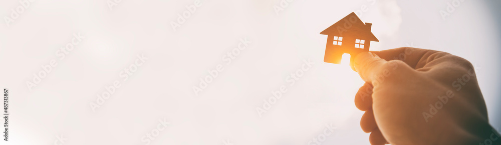 Man's hand holds wooden flat house against the sun Stock Photo | Adobe ...