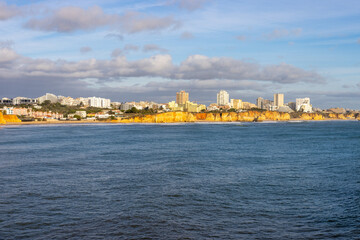Wall Mural - The beautiful view of the shoreline with the cliffs and the city. Portimao, Portugal.