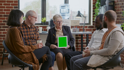 Wall Mural - Psychotherapist and patients looking at green screen on digital tablet, attending aa meeting. Woman therapist holding mockup template and isolated background on chroma key device