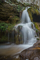 Canvas Print - A small waterfall flowing over mossy rocks