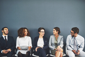 Sticker - Connecting before theyre called in. Studio shot of a group of businesspeople talking while waiting in line against a gray background.