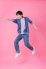 Wall Mural - Young Asian man jumping on blue background