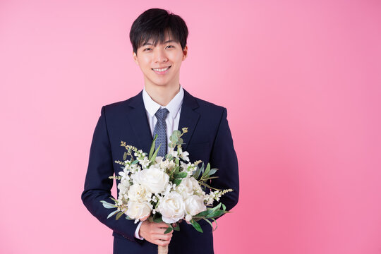 young asian groom posing on pink background