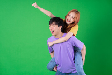 Wall Mural - Young Asian couple posing on green background