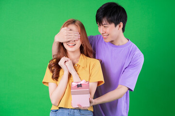 Wall Mural - Young Asian couple posing on green background