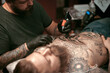 © Mr. Prof - Master does tattoo on the skin of his client in tattoo parlour