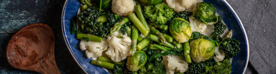 Narrow view of a dish of steamed greens and cruciferous vegetables.