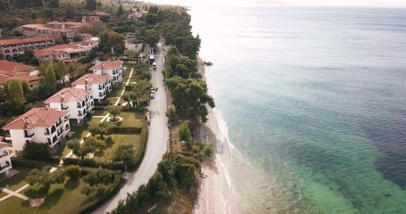 Wall Mural - Aerial video of the idyllic sea shore on the Sithonia peninsula in Halkidiki. High above the roofs of the resort village with villas and hotels with swimming pools.