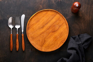 Wall Mural - Vintage silverware. Rustic vintage set of wooden spoon and fork on wooden platter on black wooden background. Empty dishes. Top view. Mock up.