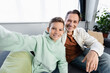 © LIGHTFIELD STUDIOS - Cheerful boy and man looking at camera while sitting on couch at home