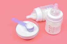 Baby Milk Bottles With Mixture And Baby Milk Formula In The Jar On Pink Background. Powdered Milk Dairy Food For Newborn
