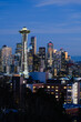 Seattle - February 11, 2022;  Seattle city skyline lights up at dusk behind the Space Needle under a blue sky