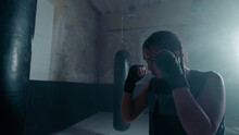 Isolated Tough Looking Young Ethnic Woman With Braids Training In A Kick Boxing Studio, Wearing Gloves, Looking Confident And Concentrated As She Trains Hard.
Fitness, Sports, Women Training Concept.
