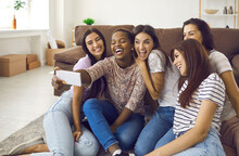 Cheerful Company Of Multiracial Female Friends Have Fun And Take Selfies During Friendly Meetings At Home. Women Sitting In The Living Room On The Floor, Record Their Moments Of Life On A Mobile Phone