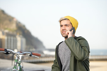 Wall Mural - Young hispanic man talking on phone outdoors