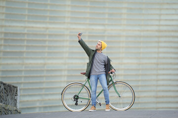 Wall Mural - Hispanic man taking a selfie while holding a classic bicycle.