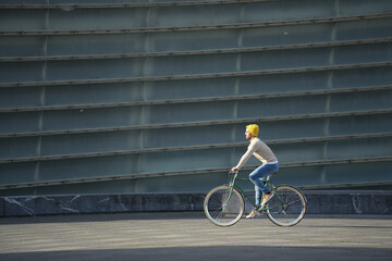 Wall Mural - Hispanic man riding an urban bicycle in the sun.