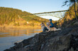 © Cavan Images - Happy female sitting with dogs on a cliff at Deception Pass