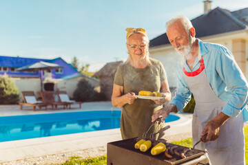 Senior couple having backyard barbecue party