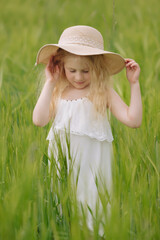 Adorable little girl playing in the wheat field on a warm summer day