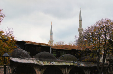 Red tile roofs of ancient buildings in Istambul. Two minarets of the mosque of Hagia Sophia in the background. Cloudy autumn day. Travel and tourism concept