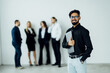 © F8  \ Suport Ukraine - Indian Business man hold laptop at the office with a group behind him